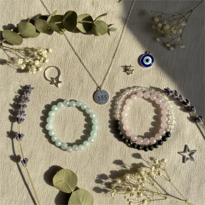 Flat lay of custom crystal bracelets an angel number 555 charm evil eye pendant and star themed jewelry representing spiritual protection and new beginnings
